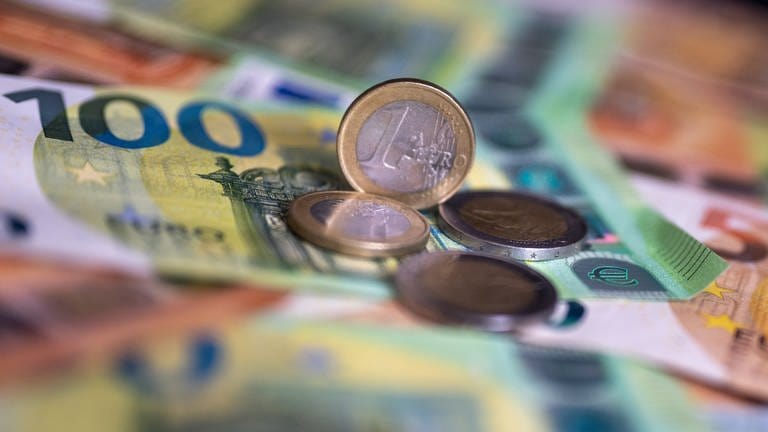 Geldscheine mit dem Wert von 100 und 50 Euro und Münzen liegen auf einem Tisch. - In Deutschland gibt es jetzt eine Haushaltssperre. Aber: Was bedeutet das?