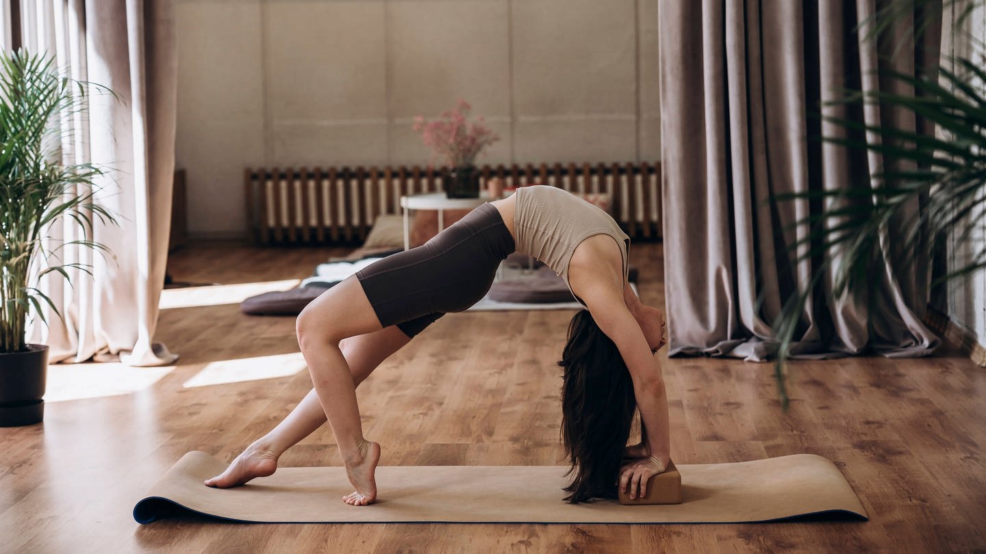 Eine junge Frau macht Yoga. Laut einer 