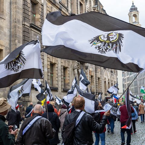 Hunderte Teilnehmer einer Demo ziehen mit Flaggen vom Königreich Preußen durch die Innenstadt. In acht Bundesländern hat es am Donnerstag eine Razzia gegen die Reichsbürger gegeben.