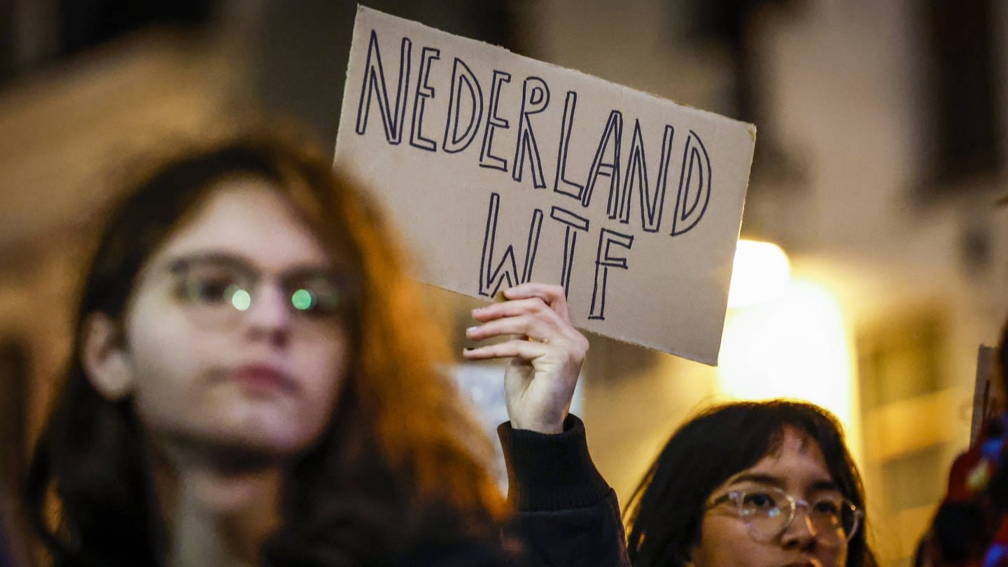 Eine Person hält bei einer Demo in den Niederlanden ein Schild hoch, auf dem steht: 