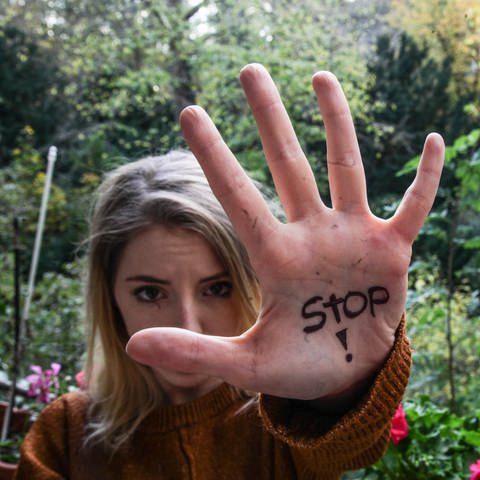 Eine Frau streckt ihre Hand, auf dem das Wort "Stop" steht, in Abwehrhaltung in die Kamera. Am Orange-Day setzen sich Menschen dafür ein, dass Frauen nicht mehr unter Gewalt leiden müssen