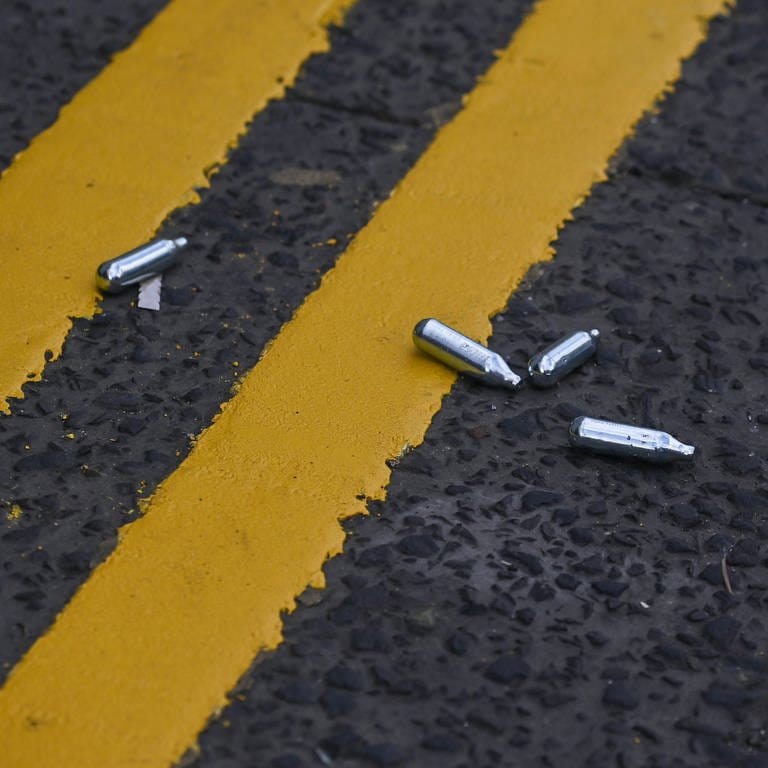 Lachgas-Kartuschen liegen auf der Straße. (Symbolbild) (Foto: IMAGO, IMAGO / NurPhoto)