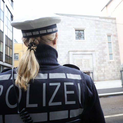 Eine Polizistin steht vor dem Gemeindezentrum sowie der Synagoge der Israelitischen Religionsgemeinschaft Württembergs (IRGS) in der Hospitalstraße in Stuttgart.