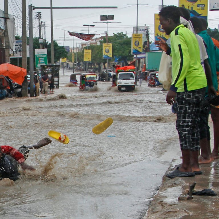Ein Mann rutscht nach starken Regenfällen im Hochwasser aus. Nach starken Regenfällen und Sturzfluten sind am Horn von Afrika über 300 Menschen getötet worden. Millionen Menschen mussten flüchten. (Foto: dpa Bildfunk, picture alliance/dpa/AP | Farah Abdi Warsameh)