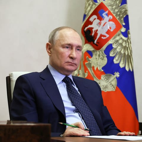 Russlands Präsident Wladimir Putin sitzt an einem Schreibtisch.