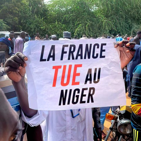 Niger, Proteste vor der Botschaft von Frankreich in Niamey. Ein Demonstrant hält ein Schild mit der Aufschrift: "France tue a Niger" d.h. auf Deutsch "Frankreich tötet Niger"