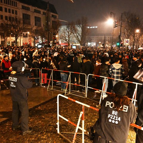 Polizisten stehen in der Silvesternacht 2021 hinter einer Absperrung am Brandenburger Tor, wo sich mehrere hundert Menschen versammelt haben. (Foto: dpa Bildfunk, picture alliance/dpa | Christophe Gateau)