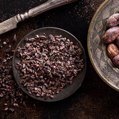 Draufsicht gemahlene Kakaobohnen Teller mit Messer Kakaobohnen (Foto: IMAGO, IMAGO / imagebroker)