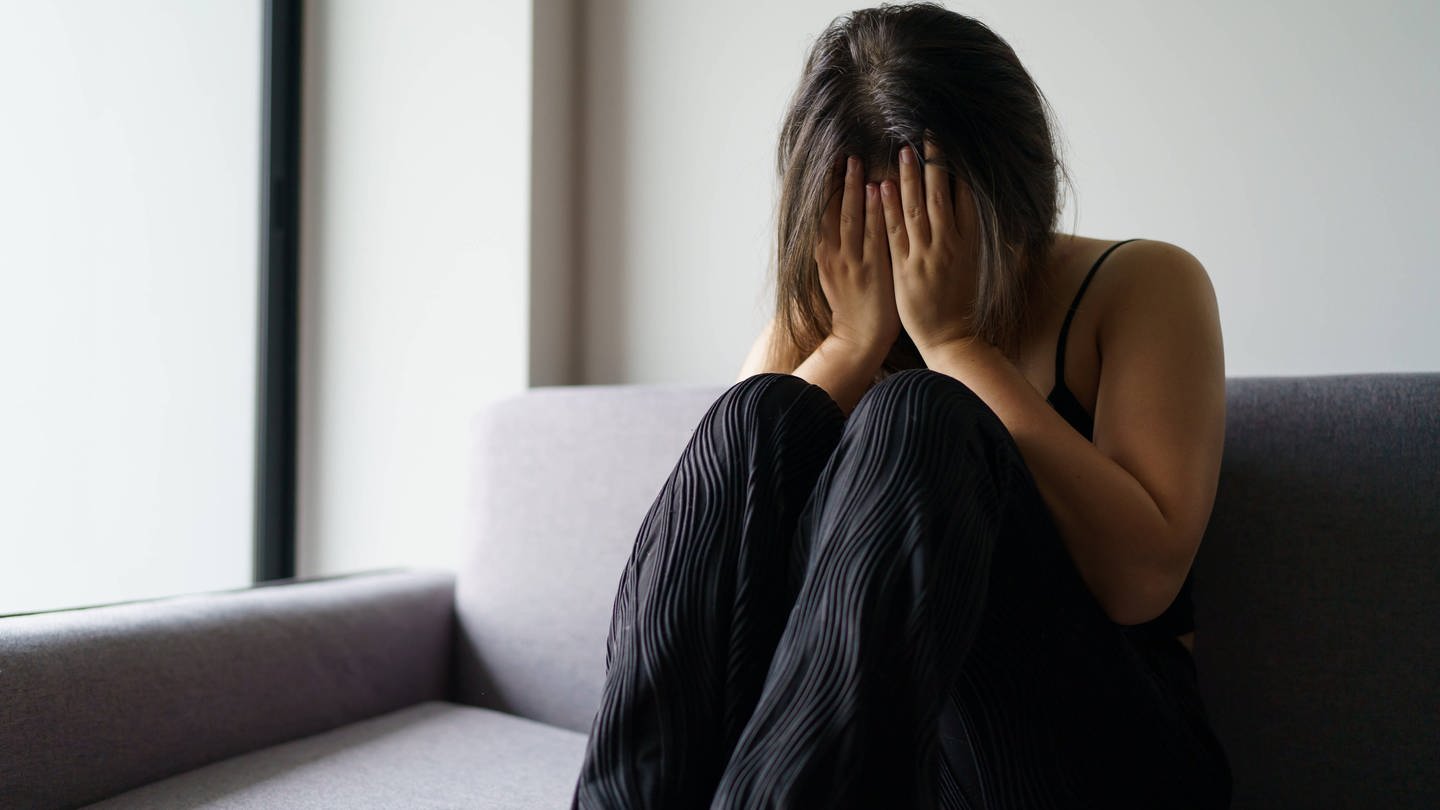 Symbolbild: Traurige Frau auf einem Sofa, die über Probleme nachdenkt. Fehltage wegen psychischer Erkrankungen haben im Jahr 2022 zugenommen. (Foto: IMAGO, IMAGO / Zoonar)
