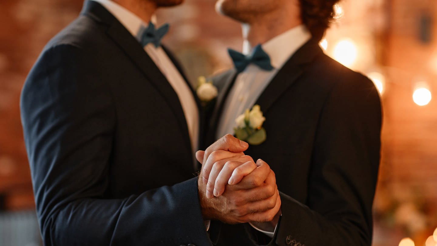 Zwei Männer tanzen zusammen auf ihrer Hochzeit und halten Händchen. (Foto: IMAGO, IMAGO / Pond5 Images)