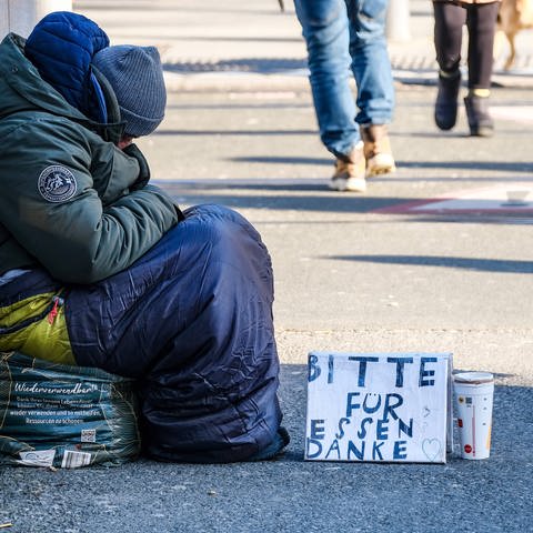 Ein Obdachloser sitzt auf der Straße und bittet um Spenden für Essen. Eine neue Studie von Oxfam zeigt: Reiche werden immer reicher, Arme immer ärmer.