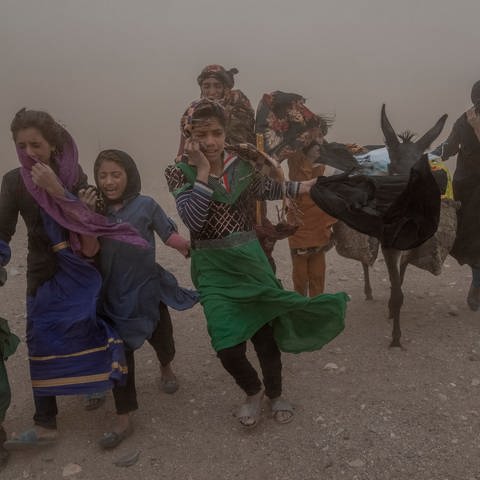 Afghanische Mädchen und Frauen tragen nach einem Erdbeben gespendete Hilfsgüter zu ihren Zelten. (Foto: dpa Bildfunk, picture alliance/dpa/AP | Ebrahim Noroozi)