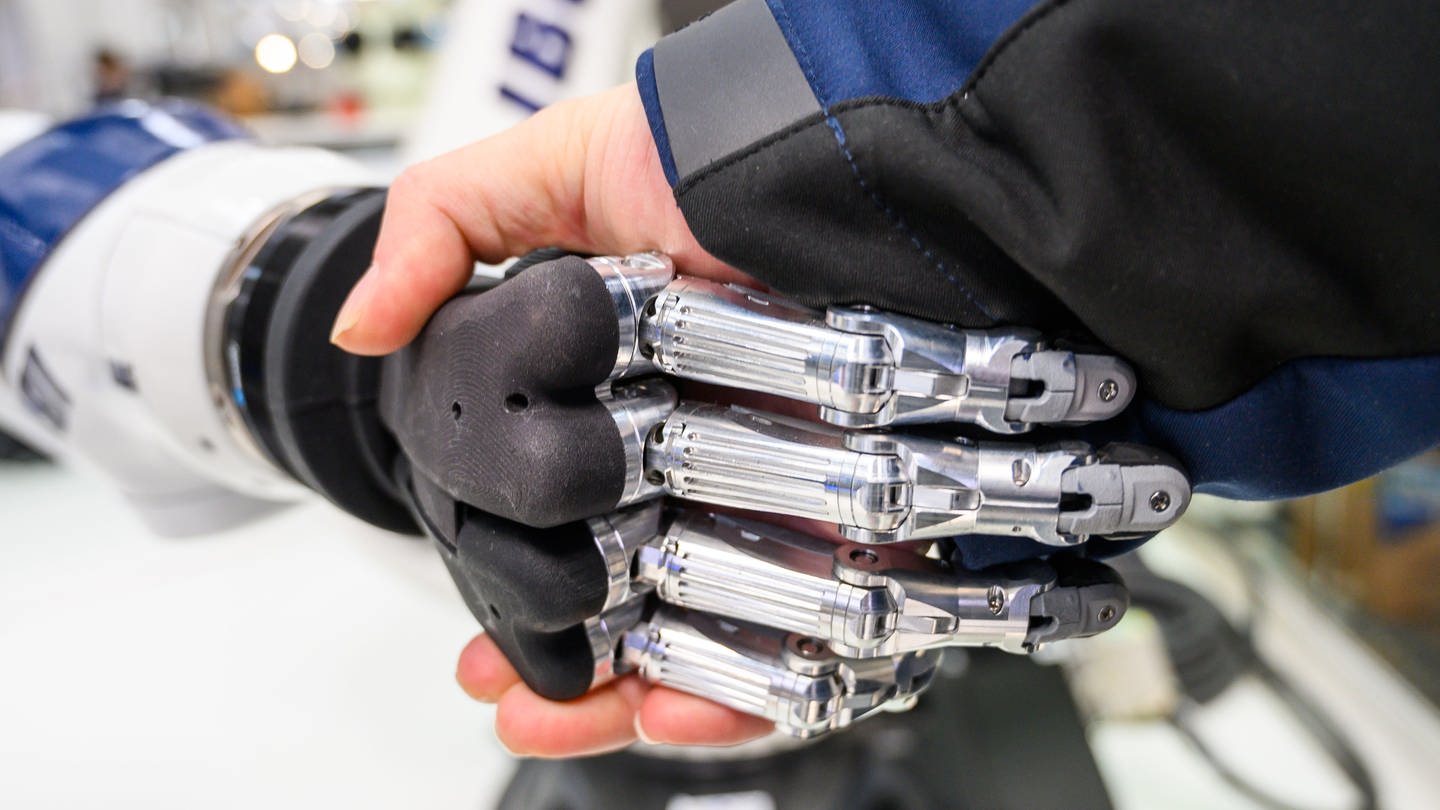 Ein Mann gibt einem Roboter die Hand - Eine Studie zeigt: KI wird sehr viele Jobs verändern (Foto: dpa Bildfunk, picture alliance/dpa | Christophe Gateau)