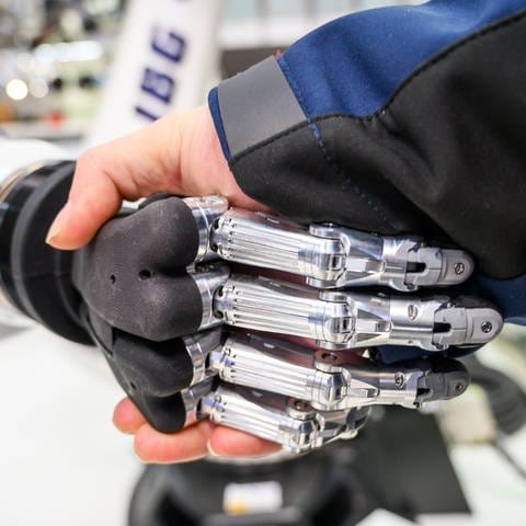 Ein Mann gibt einem Roboter die Hand - Eine Studie zeigt: KI wird sehr viele Jobs verändern
