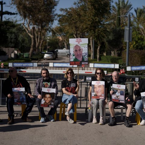 Angehörige und Freunde von Geiseln sitzen auf einer Straße vor dem Privathaus des israelischen Ministerpräsidenten Netanjahu in Caesarea. Erneut protestierten Hunderte Menschen gegen die Regierung von Ministerpräsident Netanjahu. 