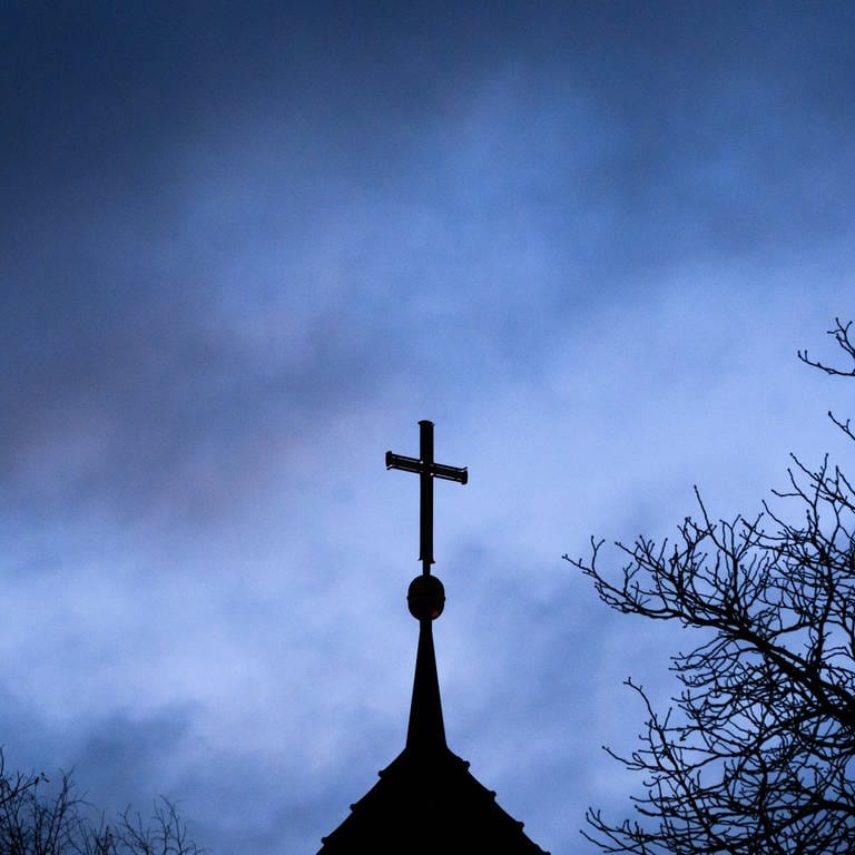 Dunkle Wolken ziehen über das Kreuz auf einer evangelischen Kirche in der Region Hannover hinweg. Der Forschungsverbund «ForuM – Forschung zur Aufarbeitung von sexualisierter Gewalt und anderen Missbrauchsformen in der evangelischen Kirche und Diakonie in Deutschland» veröffentlicht 
