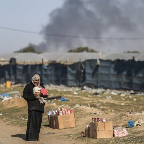 Eine Frau hält ein Kleinkind, während palästinensische Familien aufgrund israelischer Angriffe nach Rafah fliehen.