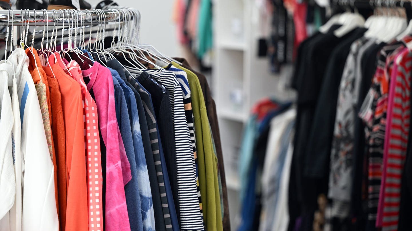 SYMBOLBILD: Auf Kleiderbügeln hängt Bekleidung in einem Modegeschäft. (Foto: dpa Bildfunk, picture alliance/dpa | Federico Gambarini)