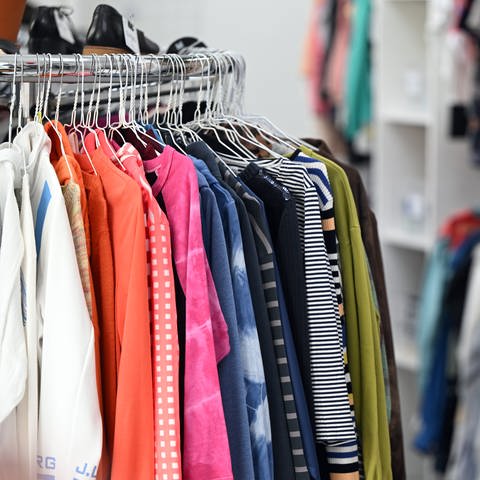 SYMBOLBILD: Auf Kleiderbügeln hängt Bekleidung in einem Modegeschäft. (Foto: dpa Bildfunk, picture alliance/dpa | Federico Gambarini)
