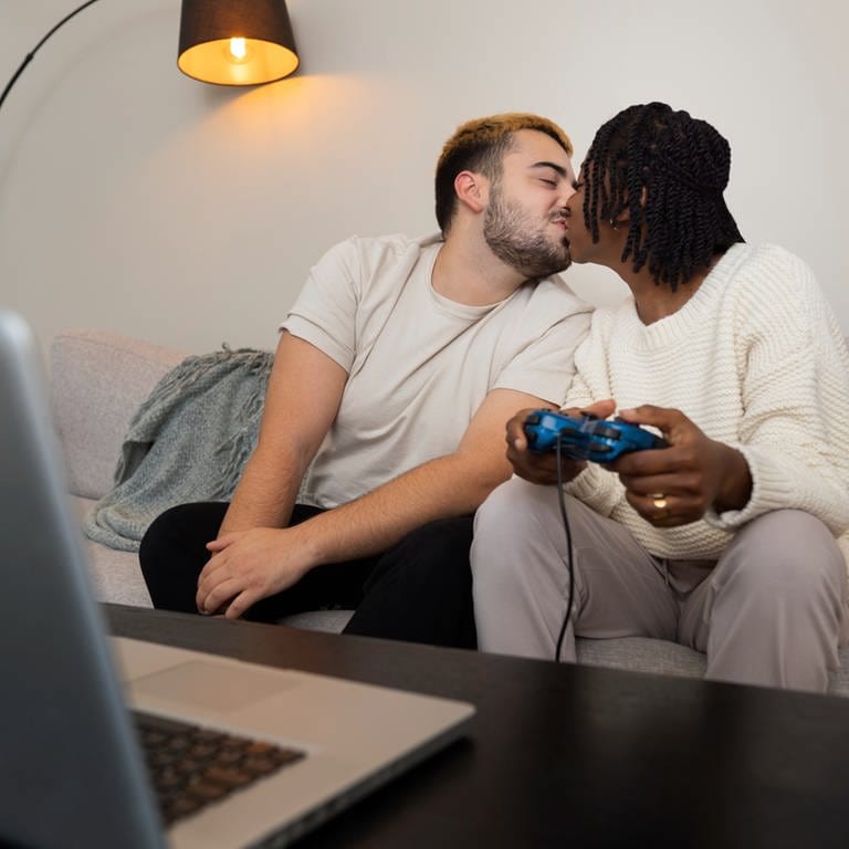 Ein Pärchen beim gemeinsamen Videospielen. Sie küssen sich. (Foto: Freepik)