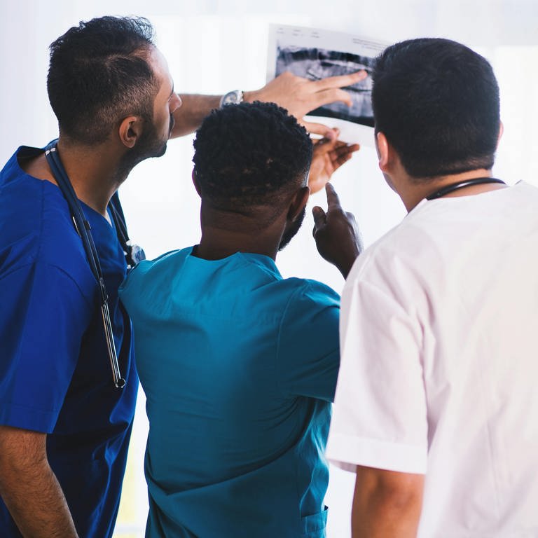 Drei Mediziner schauen sich Befunde eines Patienten an. (Foto: Pexels/EVG Kowalievska)