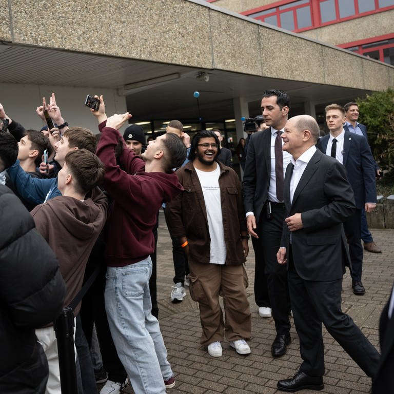 Bundeskanzler Olaf Scholz (SPD, r) geht während eines Besuchs der Gottlieb-Daimler-Schule über den Schulhof und lässt sich von Jugendlichen fotografieren. (Foto: dpa Bildfunk, picture alliance/dpa | Marijan Murat)