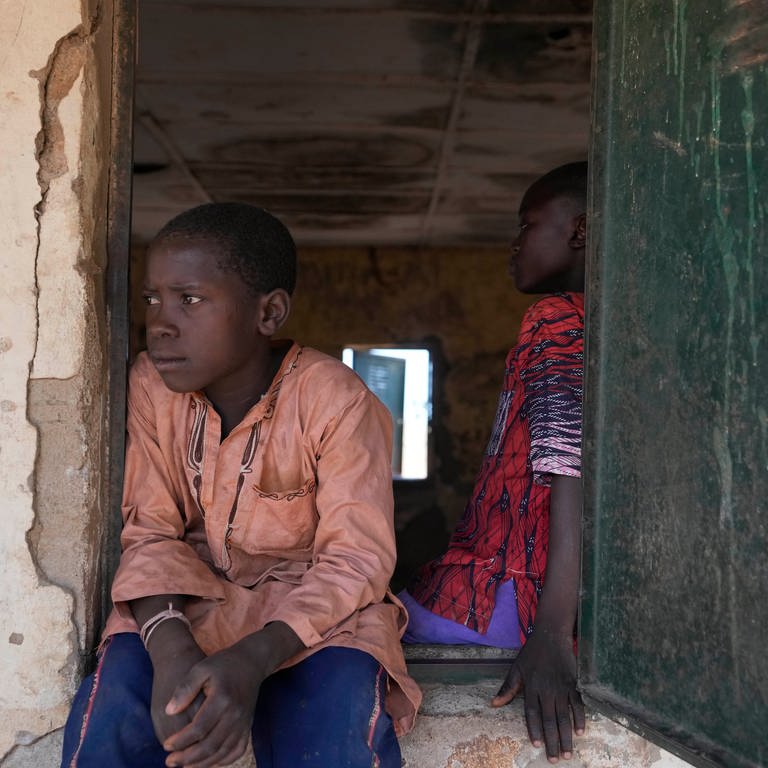 Ein Kind sitzt an einem Fenster eines Klassenzimmers in der LEA Primary and Secondary School Kuriga. Bei Angriffen an Schulen von bewaffneten Gruppen sind hunderte Schulkinder verschleppt worden. (Foto: dpa Bildfunk, picture alliance/dpa/AP | Sunday Alamba)