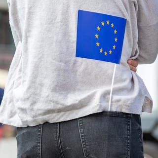Eine junge Frau hat eine Europa-Fähnchen in der rechten Hosentasche