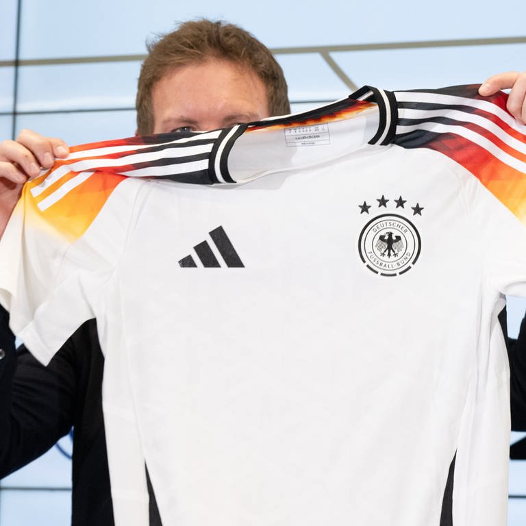 Bundestrainer Julian Nagelsmann hält auf einer Pressekonferenz das neue offizielle EM-Trikot des DFB-Teams hoch.  (Foto: dpa Bildfunk, picture alliance/dpa | Boris Roessler)