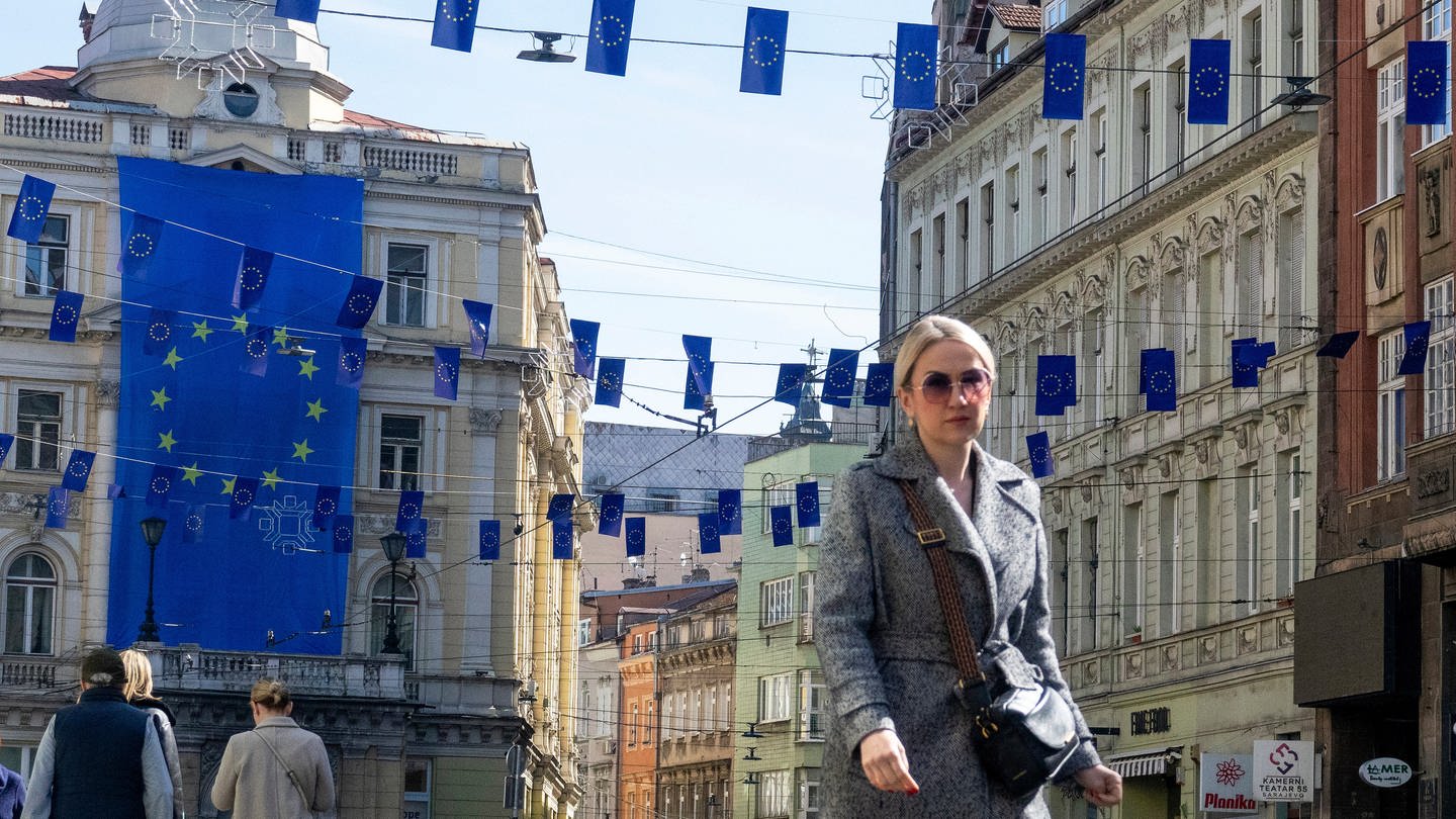 Eine Frau geht unter den Flaggen der Europäischen Union in Sarajevo. Beim EU-Gipfel wurde entschieden, dass Beitrittsverhandlungen mit Bosnien-Herzegowina gestartet werden sollen. (Foto: dpa Bildfunk, picture alliance/dpa/AP | Eldar Emric)