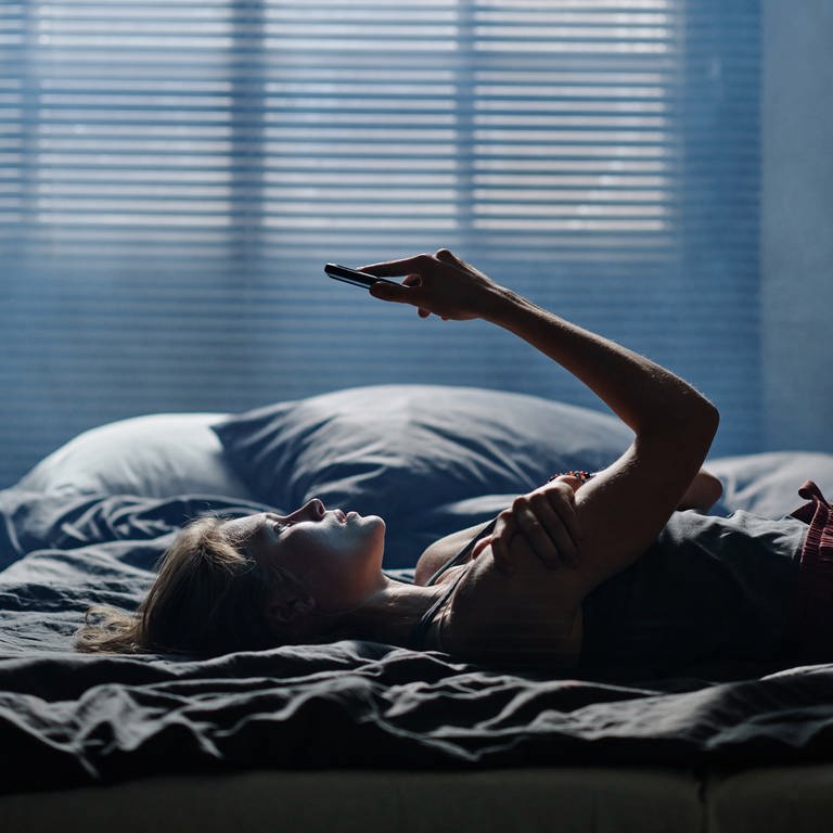 Mädchen liegt im Bett mit Handy (Foto: IMAGO, IMAGO / Pond5 Images)