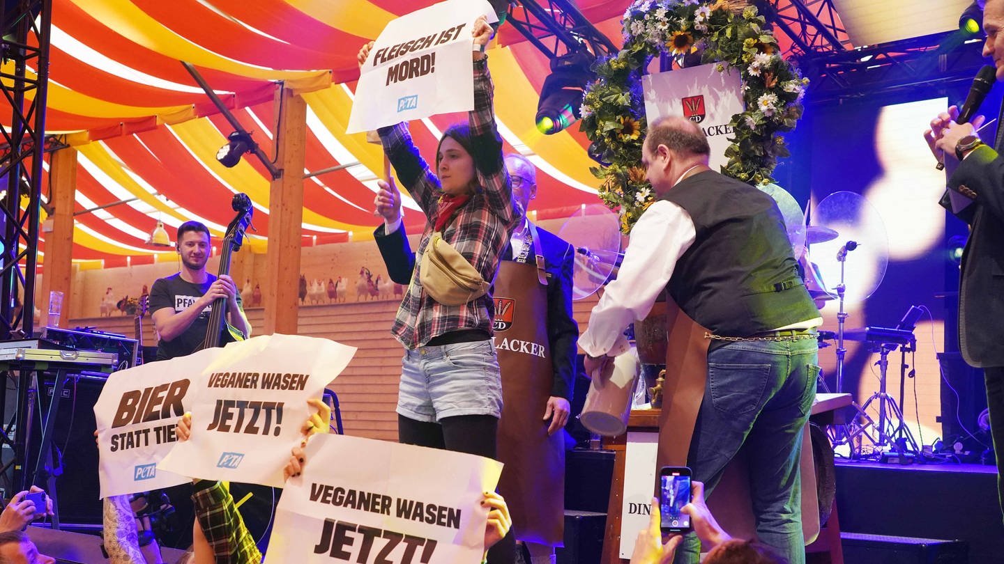 Aktivisten von Peta stören beim Frühlingsfest den Fassanstich und halten Plakate mit der Aufschrift 