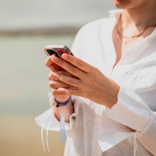 SYMBOLBILD: Eine Frau hält ein Smartphone in der Hand. (Foto: IMAGO, IMAGO / Cavan Images)