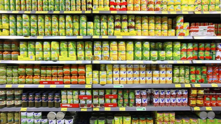 SYMBOLBILD: Lebensmittelabteilung in einem großen Supermarkt mit einem Regal mit Auswahl an Konservendosen. (Foto: IMAGO, IMAGO / Jochen Tack)