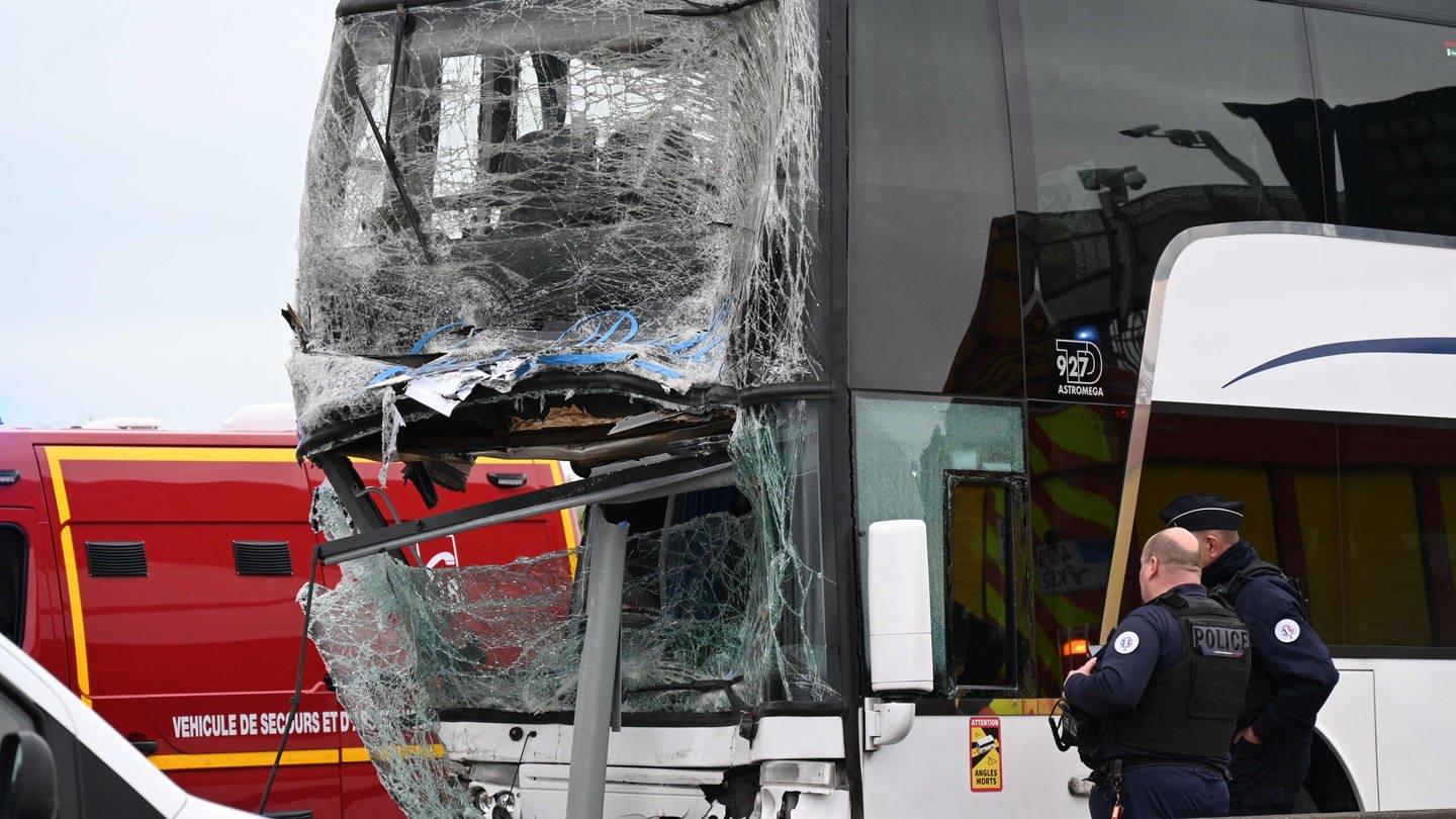 Französische Polizeibeamte stehen neben einem beschädigten Bus nach einem Unfall, an dem ein Lkw und zwei Busse mit französischen und deutschen Schülern beteiligt waren, wie die örtliche Präfektur am Freitag mitteilte. (Foto: dpa Bildfunk, picture alliance/dpa/AFP | Bernard Barron)