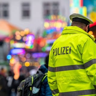 Ein Polizeibeamter steht in der Menschenmenge auf einer KerbKirmes.