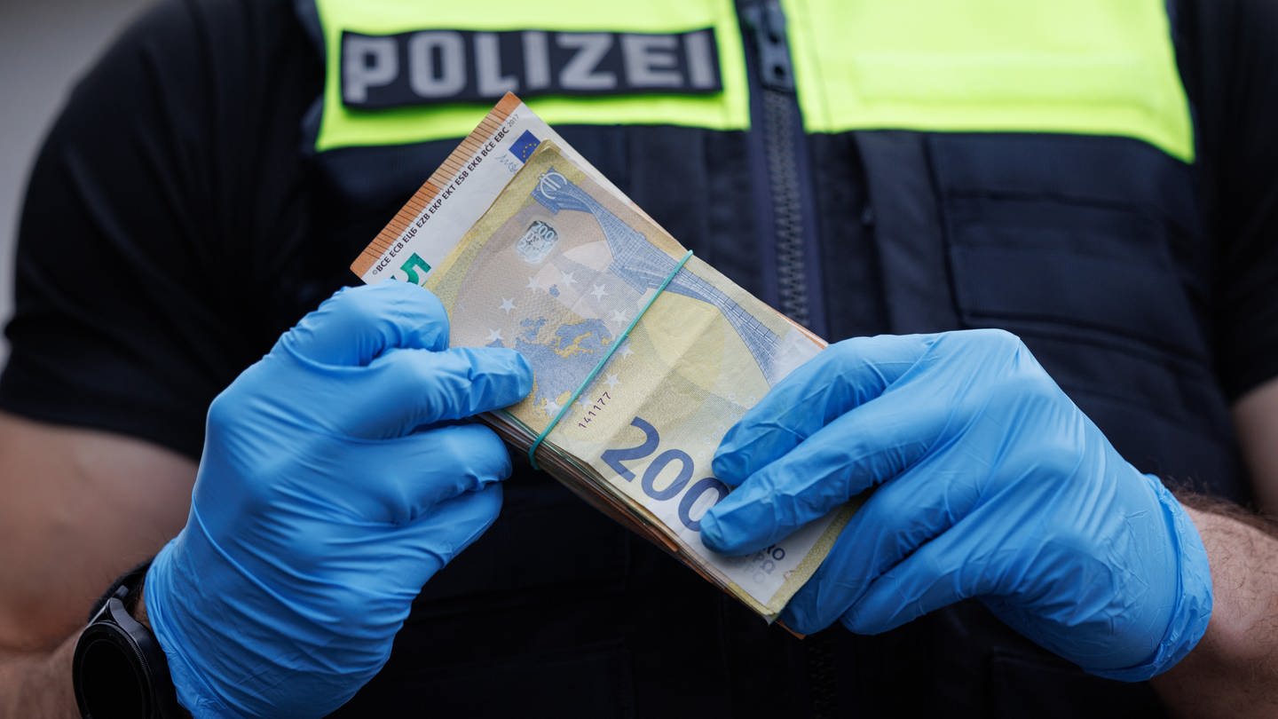 Ein Polizeibeamter mit einer größeren Menge Bargeld in der Hand. (Foto: dpa Bildfunk, picture alliance/dpa | Friso Gentsch)