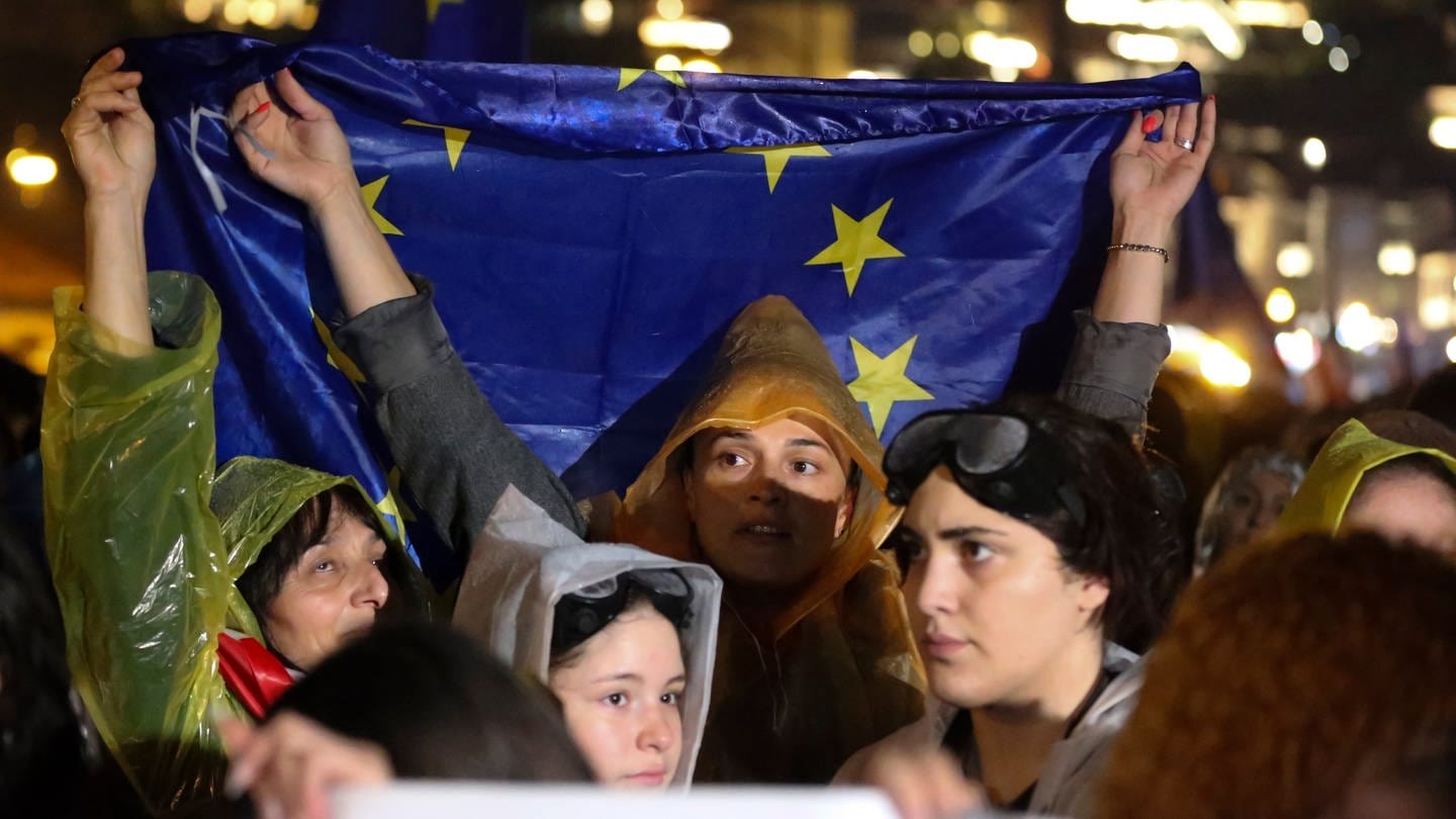 Demonstranten halten eine EU-Fahne während eines Protests gegen das sogenannte «russische Gesetz». Täglich finden Proteste gegen ein beabsichtigtes Gesetz statt, das nach Ansicht von Kritikern die Medienfreiheit einschränken und die Bewerbung des Landes zum Beitritt in die Europäische Union behindern würde. (Foto: dpa Bildfunk, picture alliance/dpa/AP | Zurab Tsertsvadze)