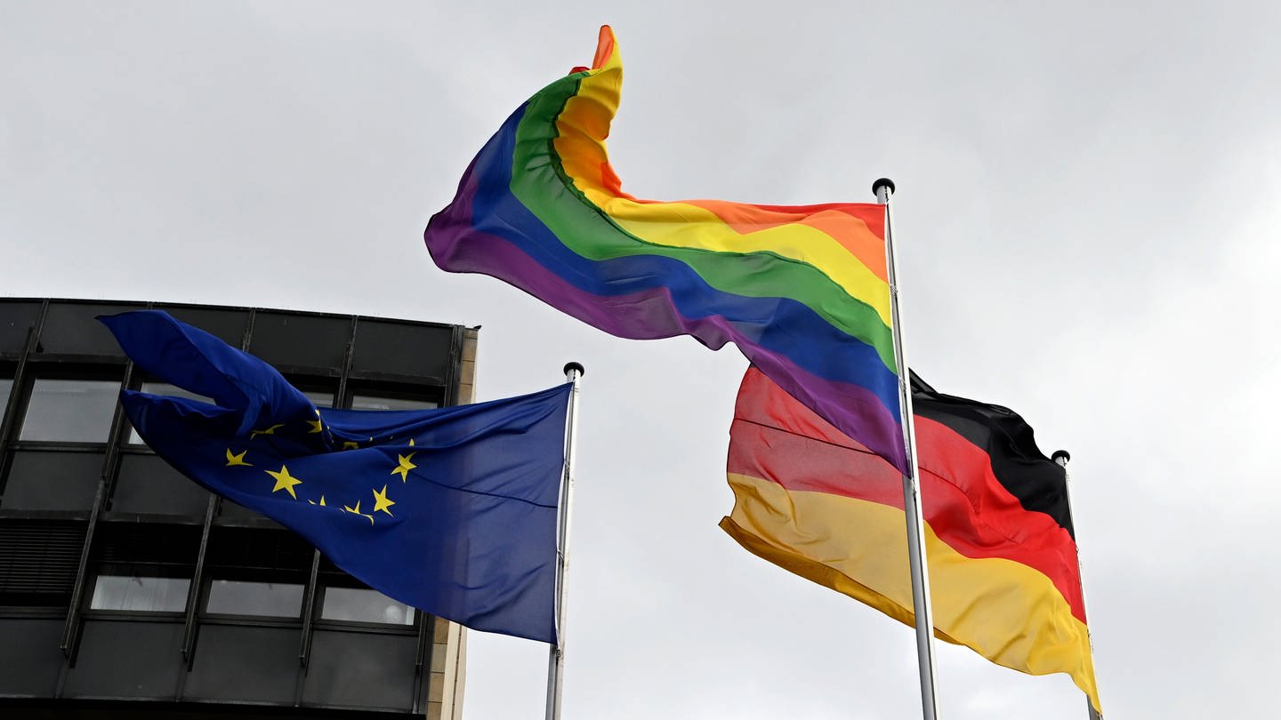 Eine Regenbogenflagge weht neben einer Deutschlandflagge und einer Europaflagge (Foto: dpa Bildfunk, picture alliance/dpa | Roberto Pfeil)