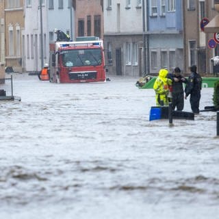Überflutete Straße im Saarland: Die Feuerwehr kämpft sich durchs Wasser, Menschen müssen evakuiert werden