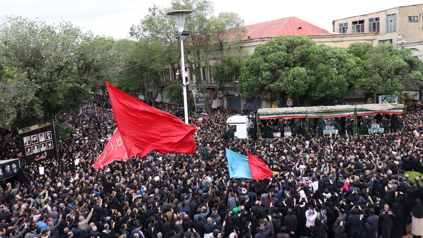 Menschen nehmen an der Trauerfeier für den verstorbenen Ebrahim Raisi teil. Ein Lkw bewegt sich langsam durch die Menge. (Foto: SWR DASDING, picture alliance/dpa | Mehrvarz Ahmadi)