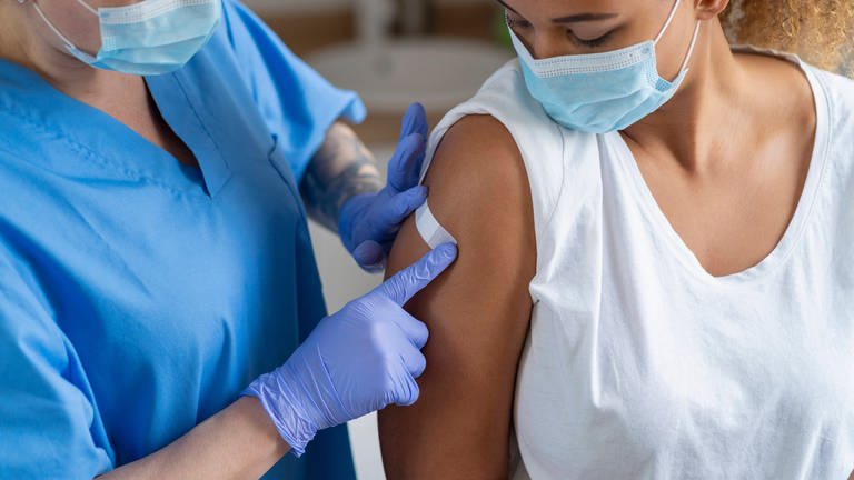 Junge Frau bekommt nach dem Impfen ein Plaster aufgeklebt (Foto: imago images, IMAGO / Westend61)