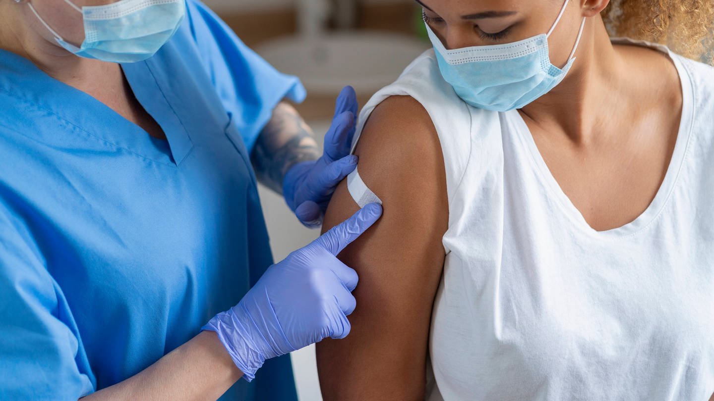 Junge Frau bekommt nach dem Impfen ein Plaster aufgeklebt (Foto: IMAGO, IMAGO / Westend61)