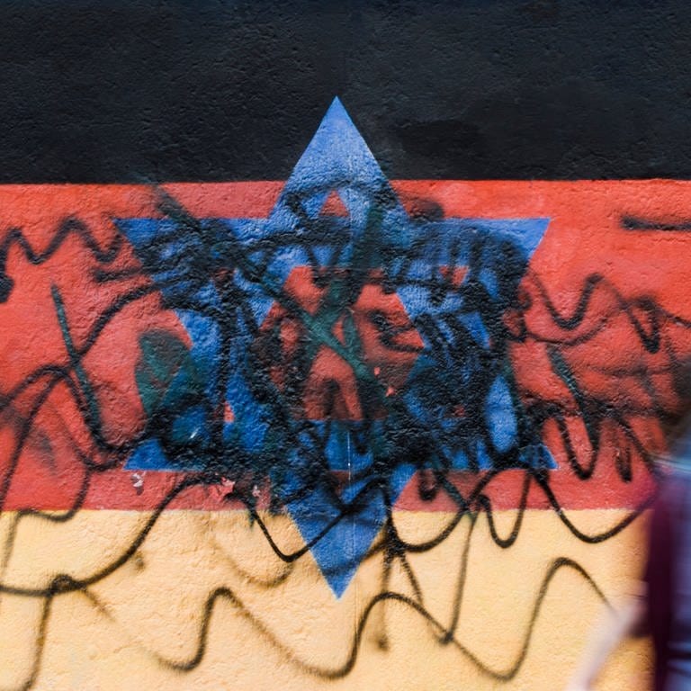 Beschmiertes Wandbild, das die schwarz-rot-goldene Deutschlandfahne mit einem blauem Davidstern zeigt (Foto: dpa Bildfunk, picture alliance/dpa | Carsten Koall)