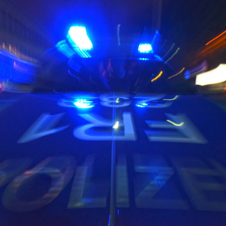 Ein Polizeifahrzeug steht mit Blaulicht auf der Straße. 