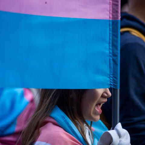 Symbolbild: Junge Person mit Trans-Flagge auf einer Demo in Madrid.