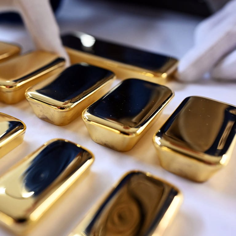 Glänzende Goldbarren liegen in einer Reihe nebeneinander.