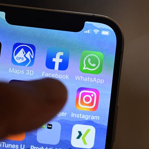 Eine Hand hält ein iPhone, auf dem Sozial Media Apps dargestellt sind. Eine aktuelle Studie zeigt, dass Menschen in Deutschland immer mehr Zeit online verbringen.